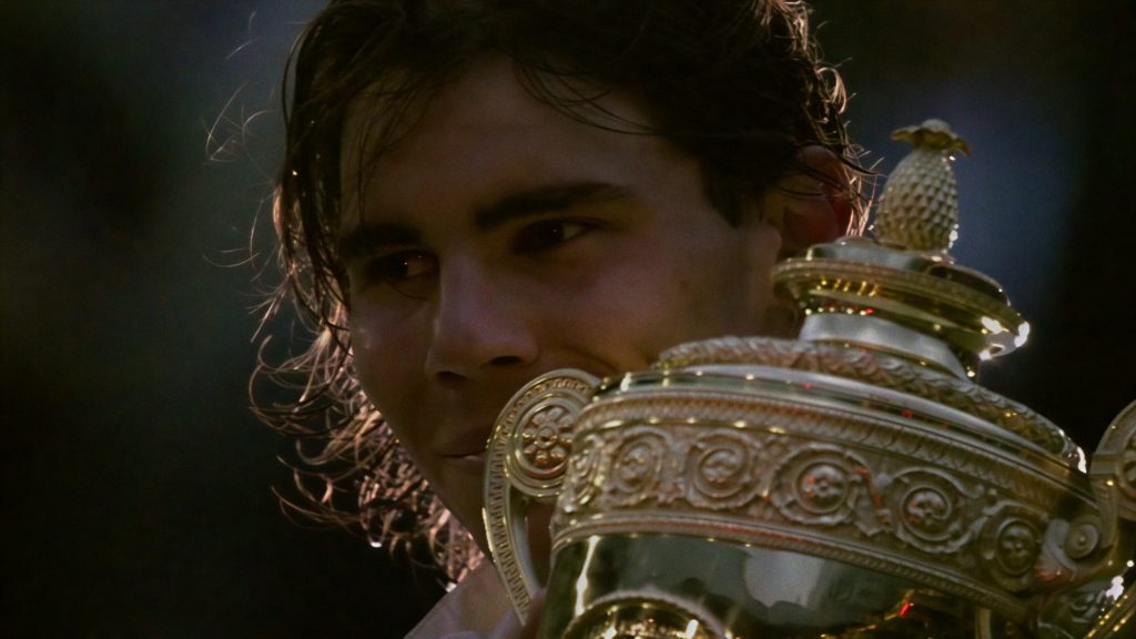 "A tennis player holding a large gold trophy, partially visible face, in an outdoor setting with dramatic lighting, celebrating a victory."